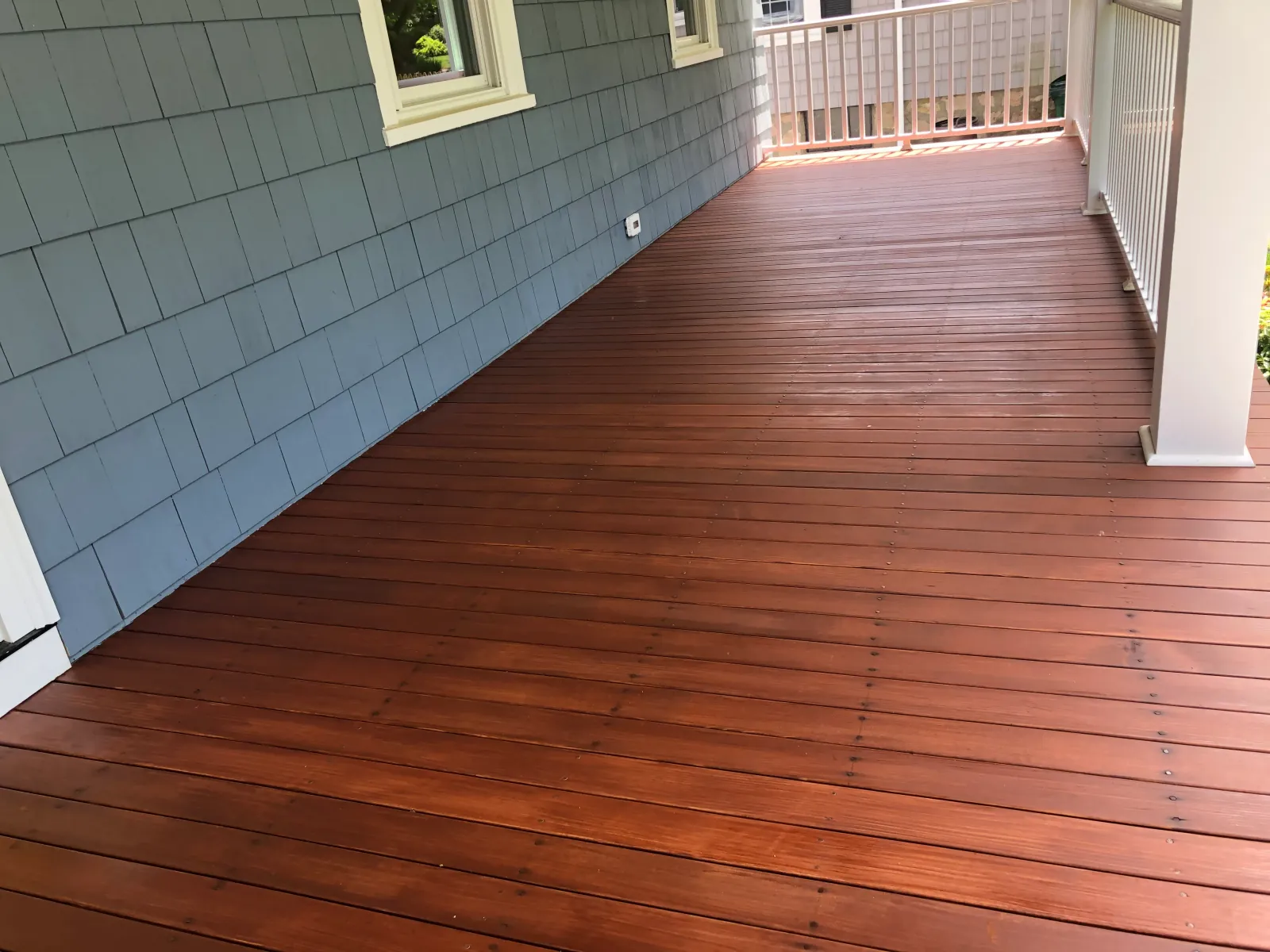 Deck staining and painting project in Massachusetts with rich cherry tone