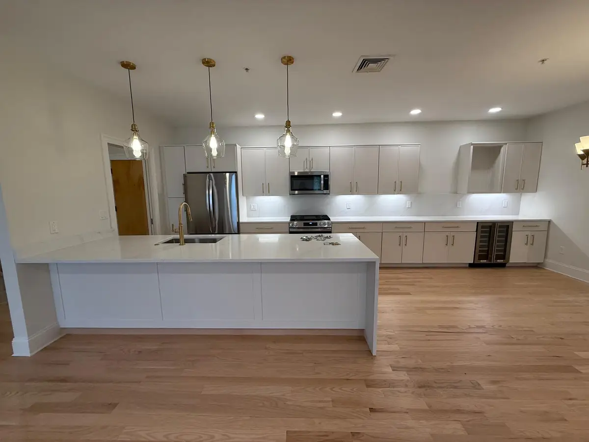 Newton, MA kitchen after cabinet painting: white cabinets with brass pulls