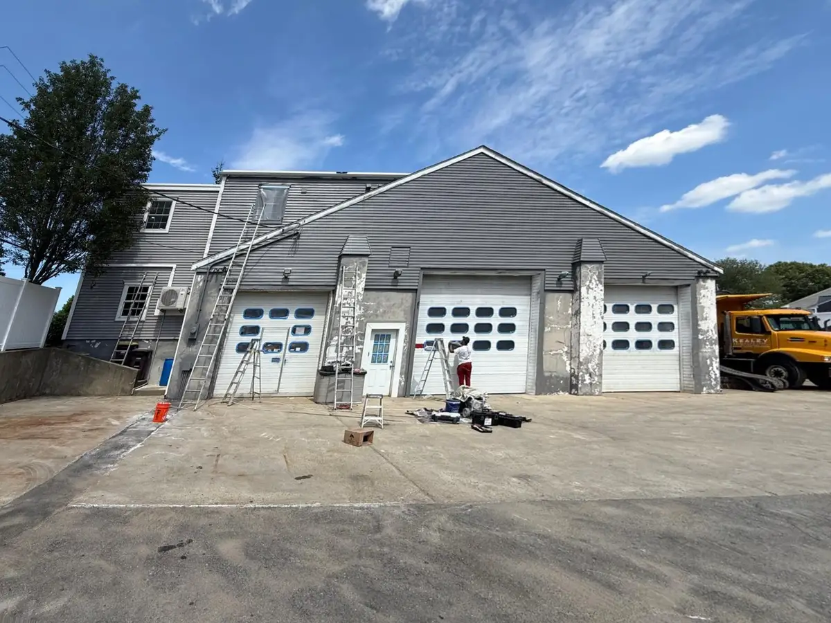 Same Weymouth garage before: white doors and peeling paint on the masonry pilasters