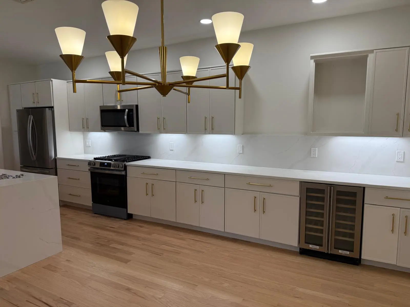 Angled view of painted white cabinets, wine fridge and range in a Newton kitchen