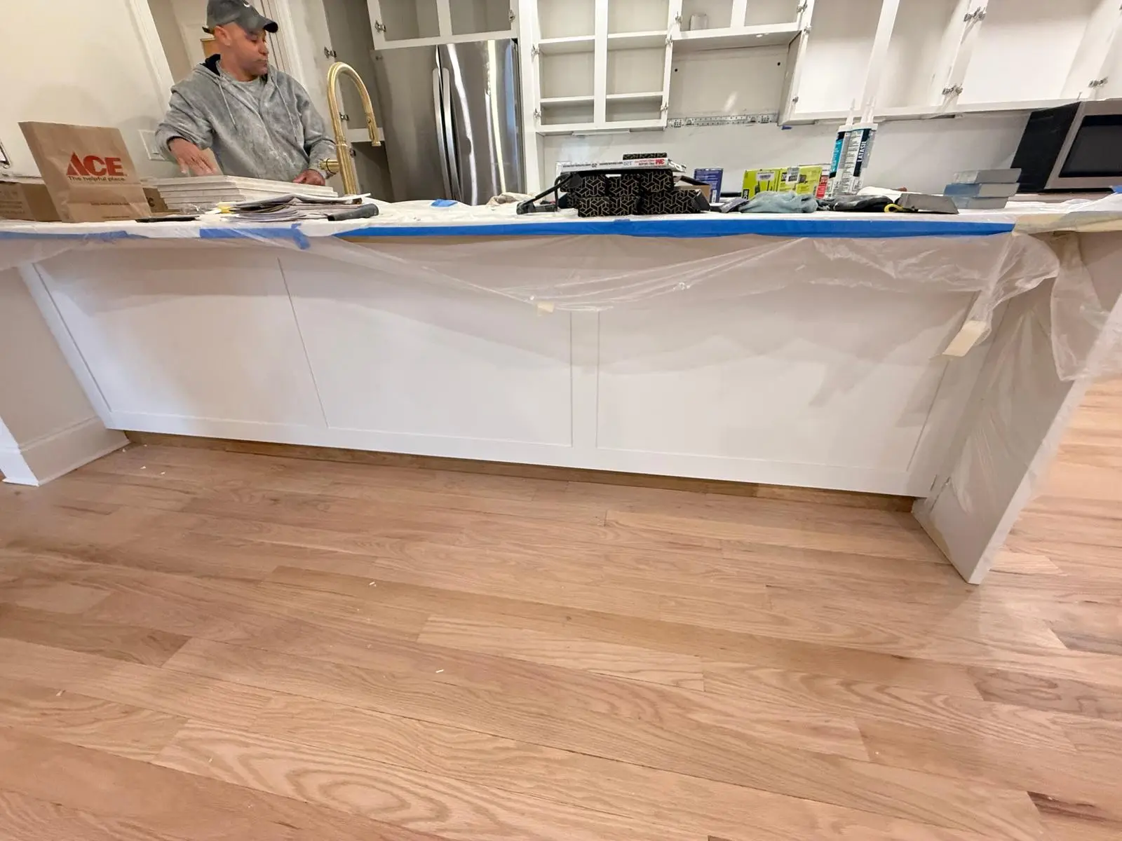 Peninsula base painted white with countertop masked in plastic during the Newton project