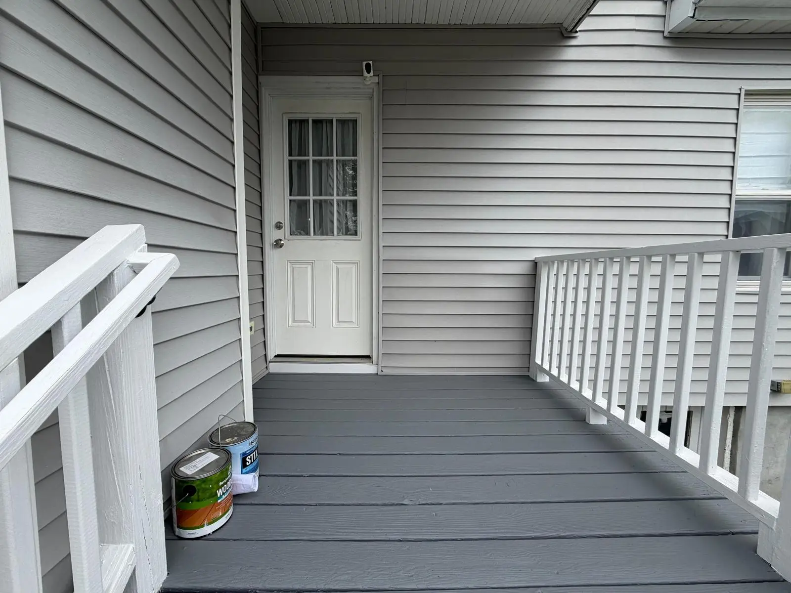 Back porch floor painted gray with white railings and back door in Norwood