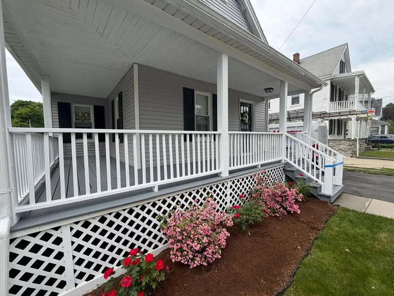 Front porch in Norwood, MA after painting: gray floor and steps, white railings, balusters and lattice skirt