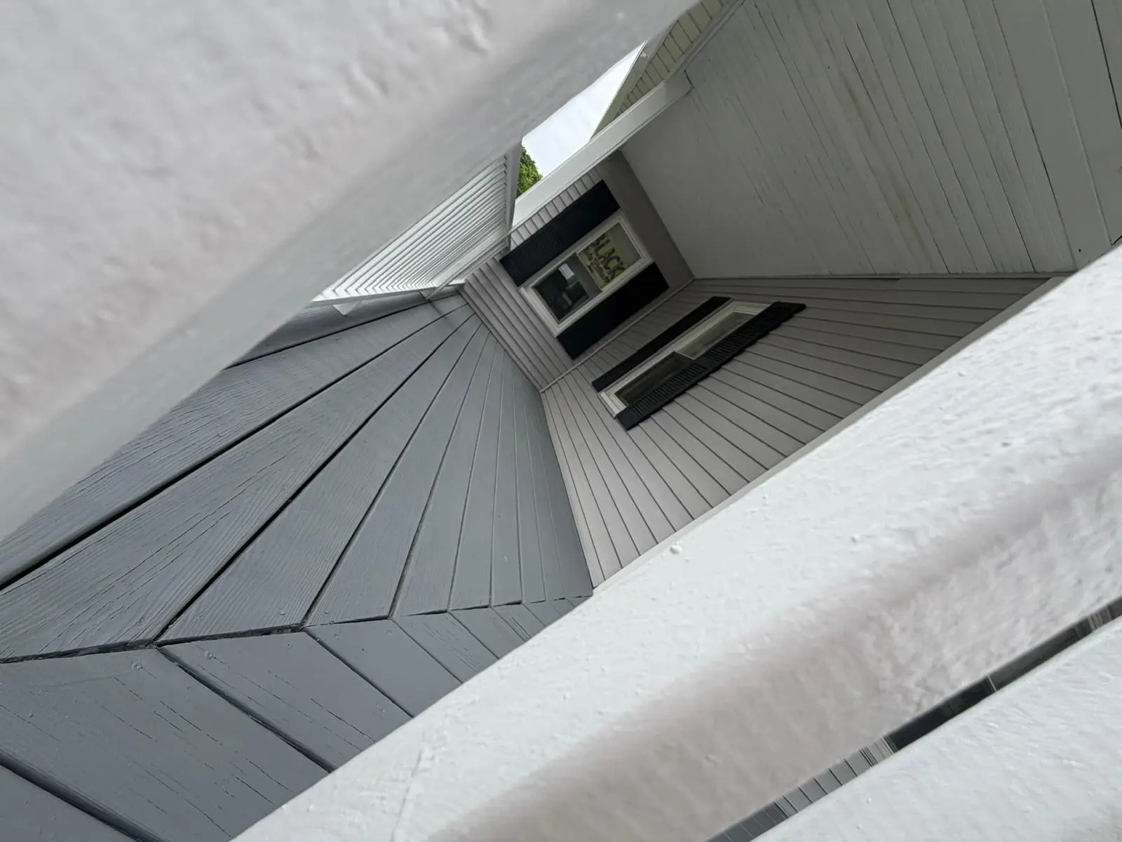 Close view of gray painted porch floor boards and white railing in Norwood