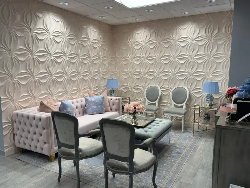 Dental office waiting room with a sculpted 3D floral feature wall, pink tufted sofa and gray chairs