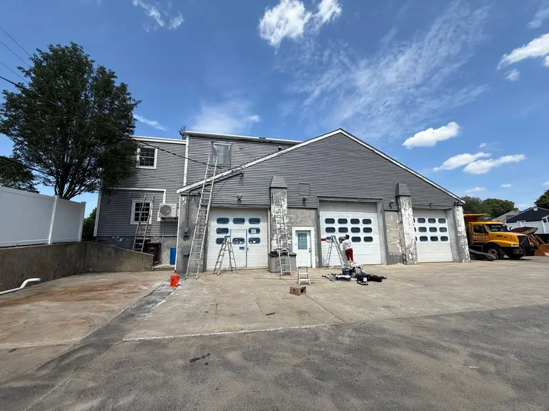Weymouth garage before painting with white overhead doors and peeling masonry pilasters